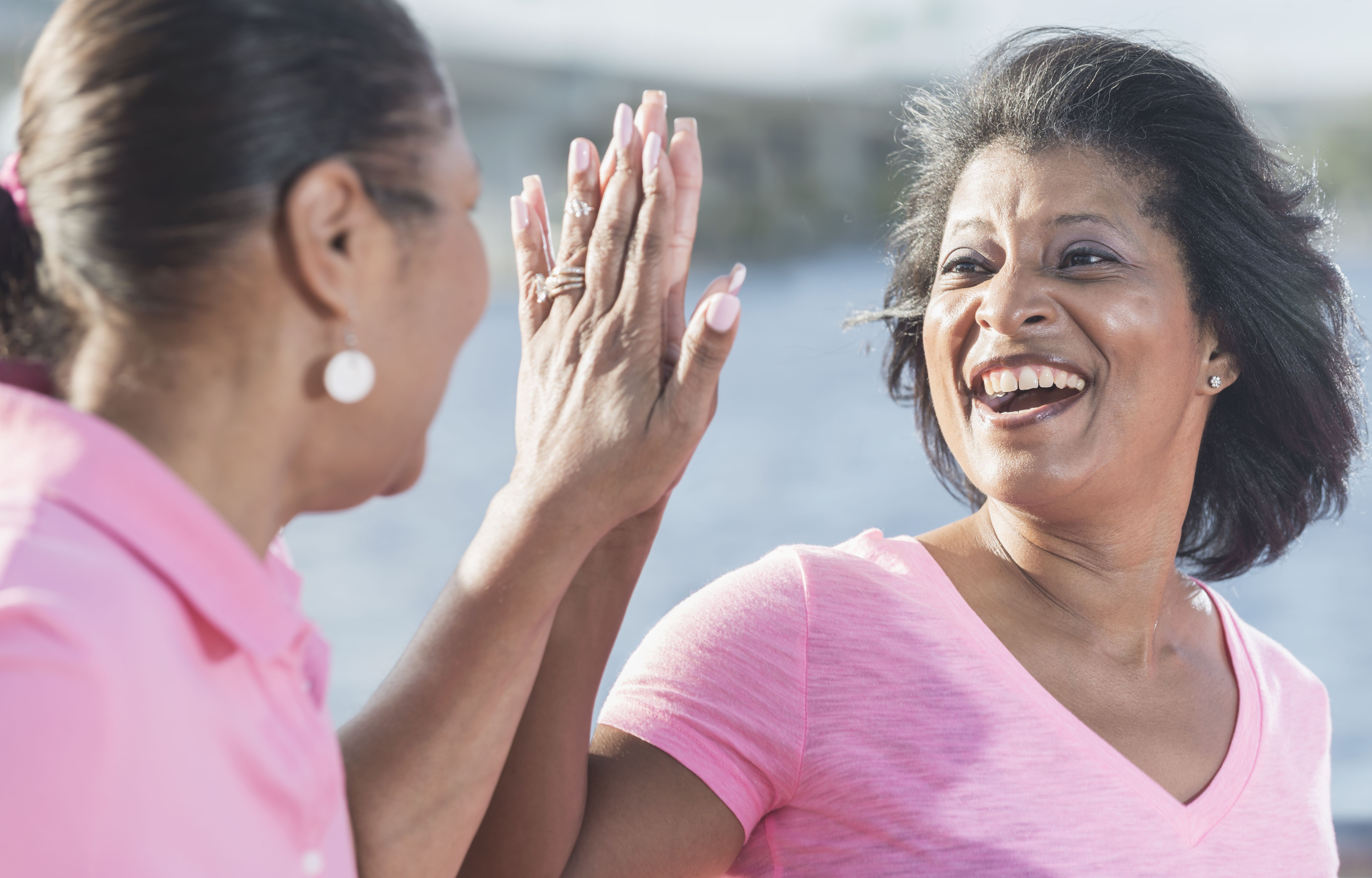 Two mature African American woman in pink, high fives