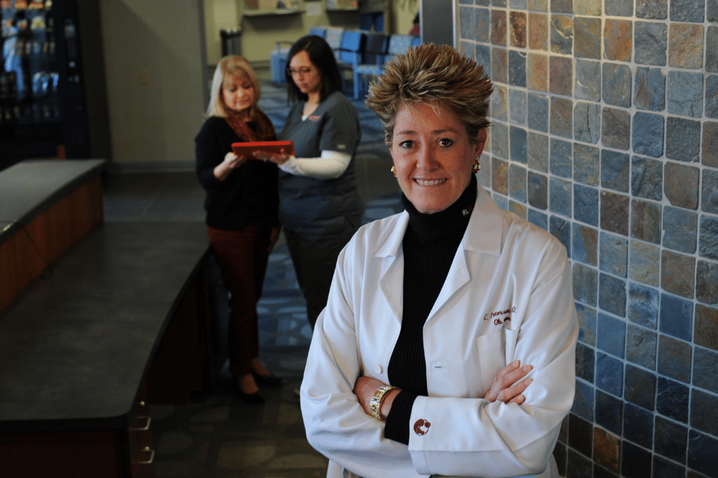 Dr. Peterson stands with arms cross, two women stand behind her