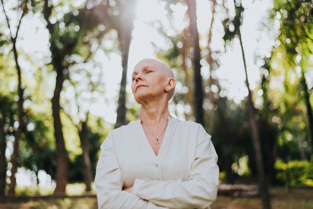 Woman with cancer in a white sweater standing in the forest