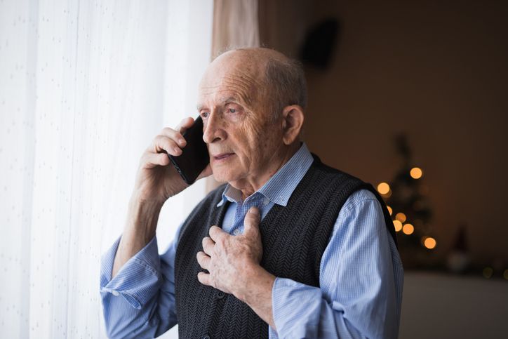 Senior talking on phone with a serious face expression and holding the chest